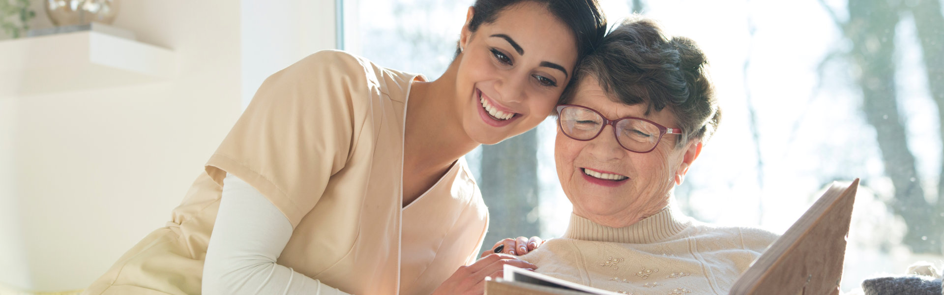 elderly woman with caregiver reading a book