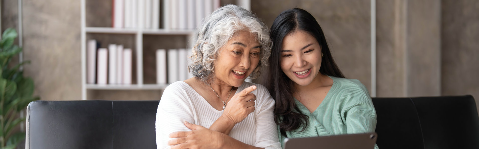 caretaker and elderly woman enjoy using laptop